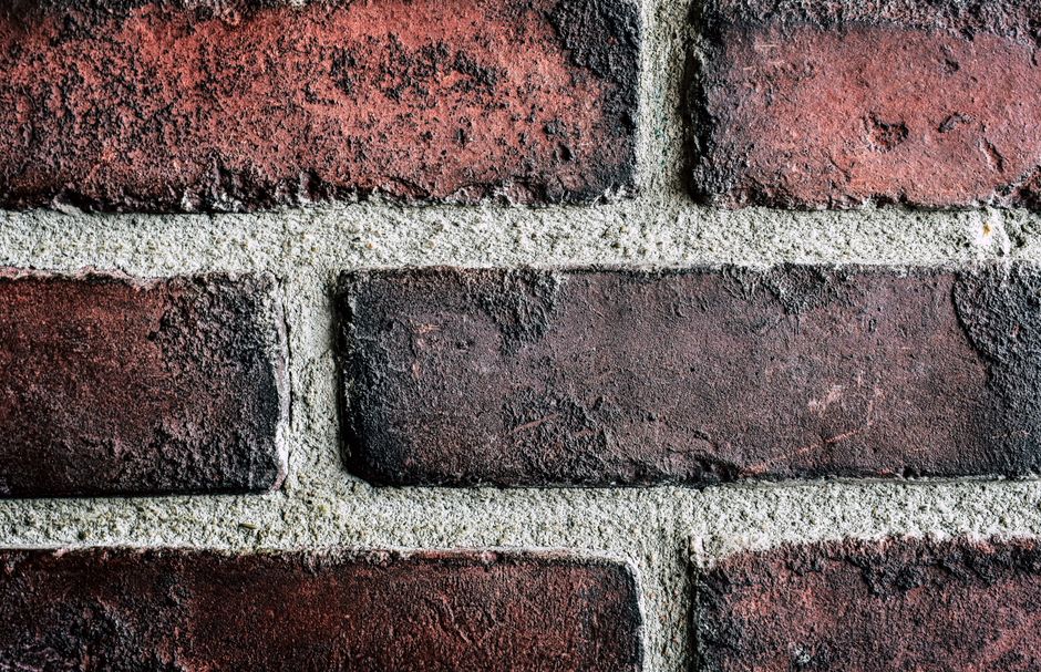 Detailed close-up of a textured red brick wall with visible mortar lines, emphasizing texture and structure.